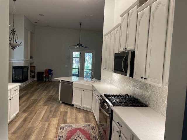 kitchen with sink, decorative light fixtures, appliances with stainless steel finishes, kitchen peninsula, and white cabinets