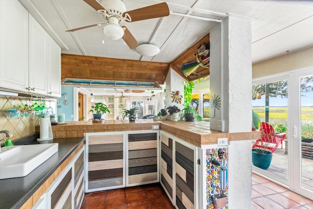 kitchen featuring white cabinets, sink, wooden walls, decorative backsplash, and kitchen peninsula