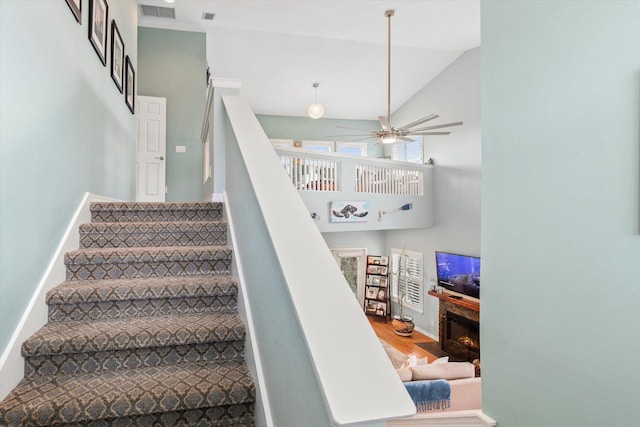 stairway with hardwood / wood-style floors, high vaulted ceiling, and ceiling fan