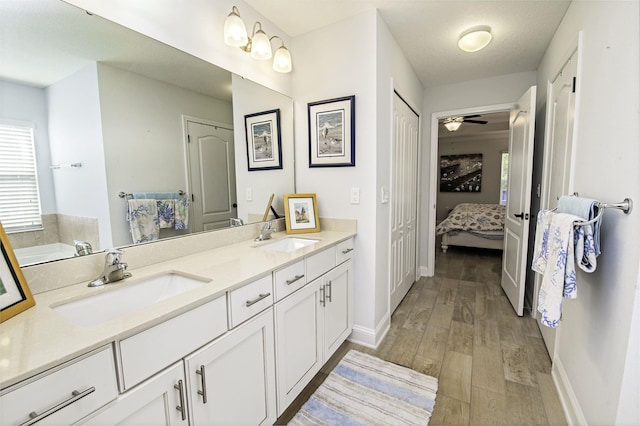 bathroom with ceiling fan, a washtub, vanity, and hardwood / wood-style flooring