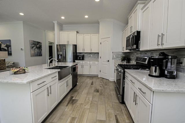 kitchen with white cabinetry, light stone countertops, appliances with stainless steel finishes, and light hardwood / wood-style flooring