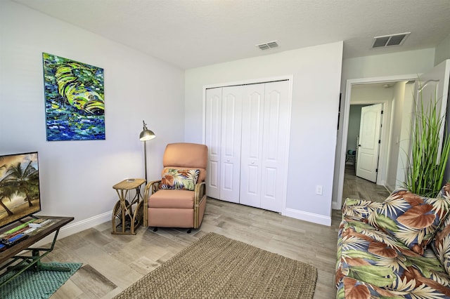 living area featuring a textured ceiling and light hardwood / wood-style floors