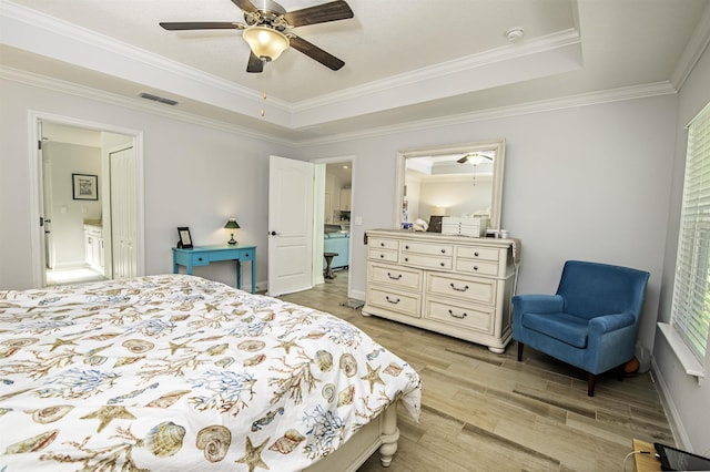 bedroom with ceiling fan, crown molding, ensuite bathroom, light hardwood / wood-style floors, and a tray ceiling