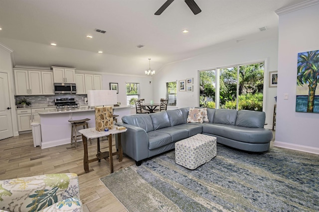 living room featuring ceiling fan with notable chandelier, light hardwood / wood-style floors, plenty of natural light, and ornamental molding