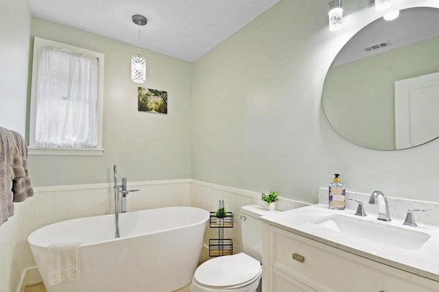 bathroom featuring a wainscoted wall, a freestanding tub, toilet, and vanity