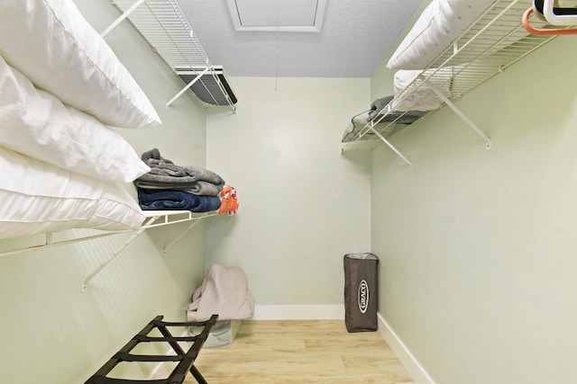 walk in closet with wood finished floors and attic access