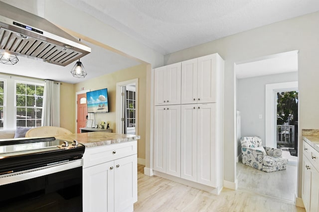 kitchen featuring stainless steel range with electric stovetop, range hood, light wood-style floors, and white cabinets