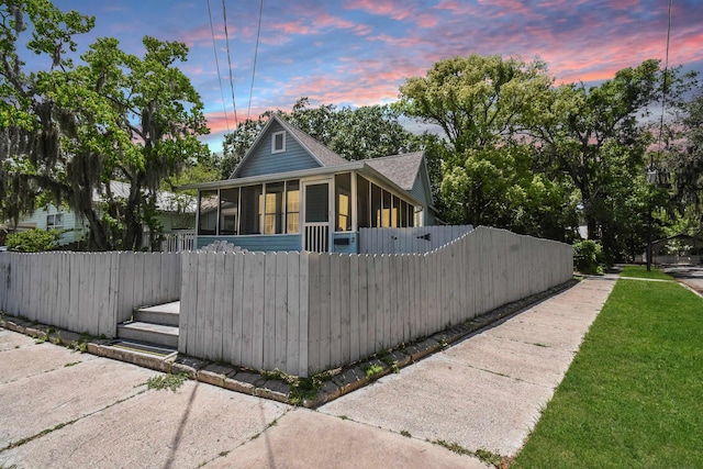 view of front of house featuring a sunroom, fence, and roof with shingles