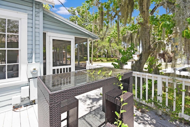 deck featuring a sunroom and outdoor dining space