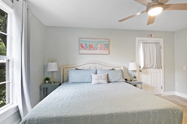 bedroom with wood finished floors, multiple windows, baseboards, and a ceiling fan