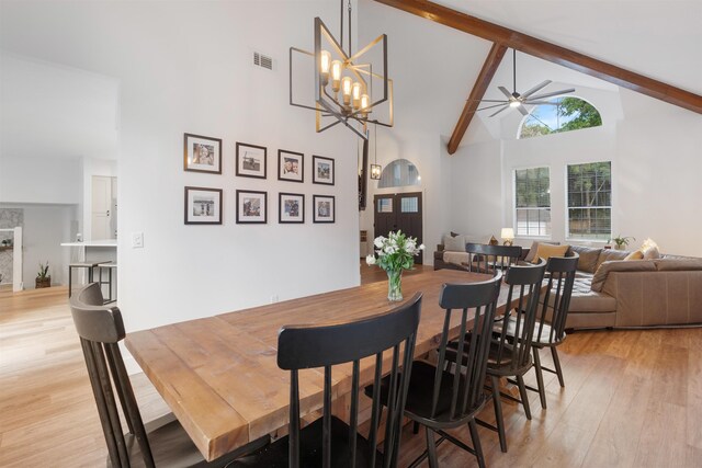 dining area featuring beamed ceiling, ceiling fan with notable chandelier, light hardwood / wood-style floors, and high vaulted ceiling