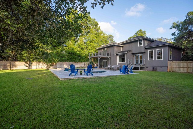 rear view of house featuring a lawn, a balcony, and a patio