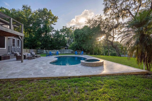 pool at dusk featuring an in ground hot tub, outdoor lounge area, a yard, and a patio area