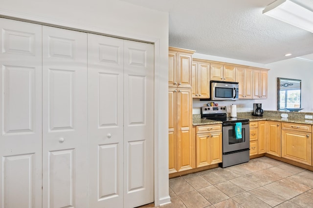 kitchen featuring stone counters, light tile patterned floors, stainless steel appliances, and light brown cabinetry