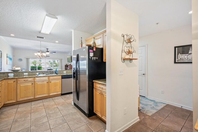 kitchen with sink, light stone counters, light tile patterned floors, and stainless steel appliances