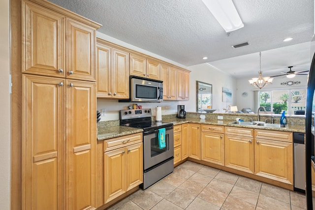 kitchen featuring stone countertops, ceiling fan with notable chandelier, sink, and appliances with stainless steel finishes