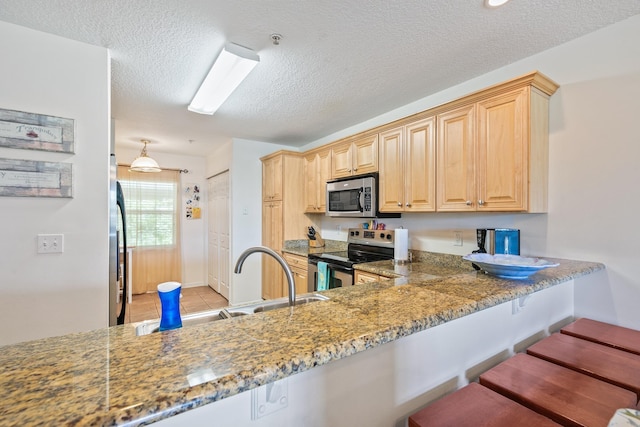 kitchen featuring kitchen peninsula, appliances with stainless steel finishes, sink, light brown cabinets, and stone counters