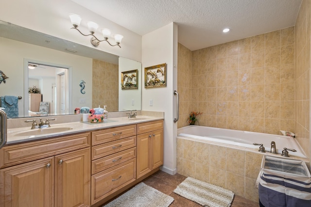 bathroom with tile patterned floors, vanity, a textured ceiling, tiled tub, and tile walls