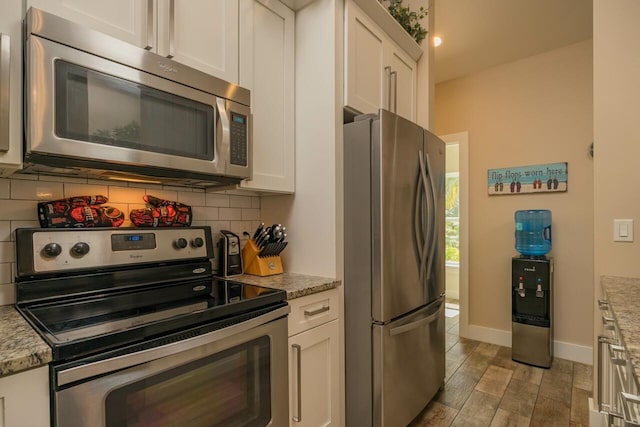 kitchen featuring appliances with stainless steel finishes, decorative backsplash, white cabinets, and light stone counters