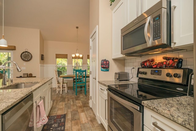 kitchen featuring a notable chandelier, pendant lighting, sink, white cabinetry, and stainless steel appliances