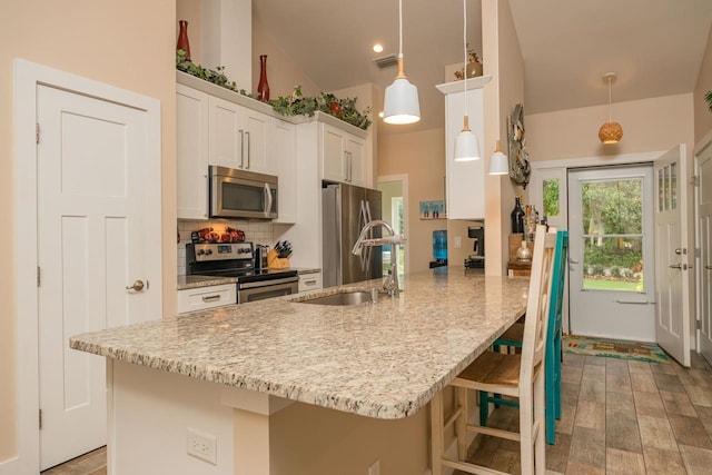 kitchen featuring appliances with stainless steel finishes, sink, white cabinetry, and pendant lighting