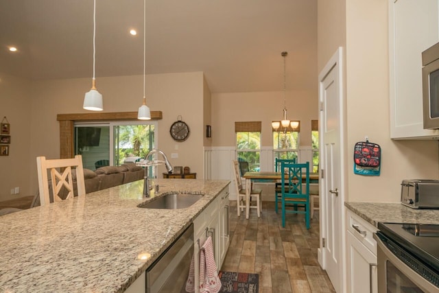 kitchen featuring light stone countertops, pendant lighting, appliances with stainless steel finishes, white cabinetry, and sink