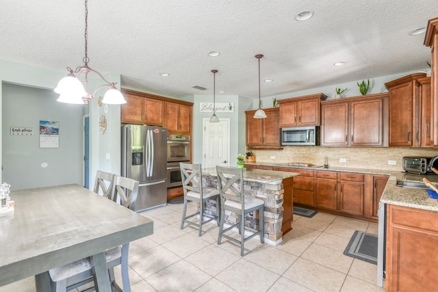 104 Claremont Ct, Elkton, FL 32033 - kitchen with appliances with stainless steel finishes, decorative backsplash, a kitchen island, brown cabinetry, and a textured ceiling