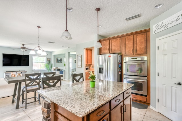 104 Claremont Ct, Elkton, FL 32033 - kitchen with appliances with stainless steel finishes, brown cabinets, open floor plan, light stone counters, and a kitchen island
