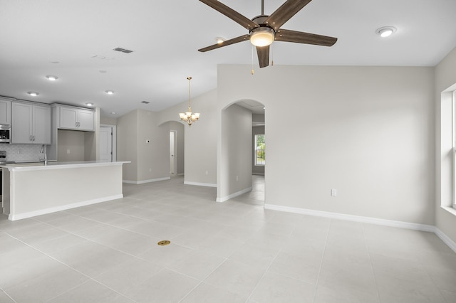 unfurnished living room with lofted ceiling, sink, ceiling fan with notable chandelier, and light tile patterned floors