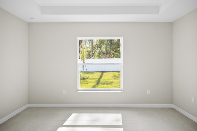 empty room with light tile patterned floors and a raised ceiling