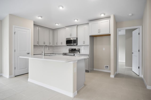 kitchen featuring appliances with stainless steel finishes, sink, an island with sink, and backsplash