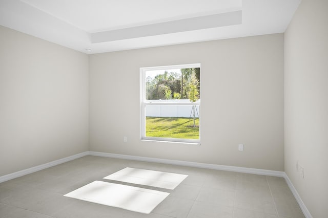 unfurnished room with a raised ceiling and light tile patterned floors