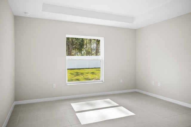 tiled spare room with a raised ceiling