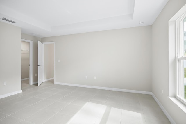 tiled empty room featuring a tray ceiling