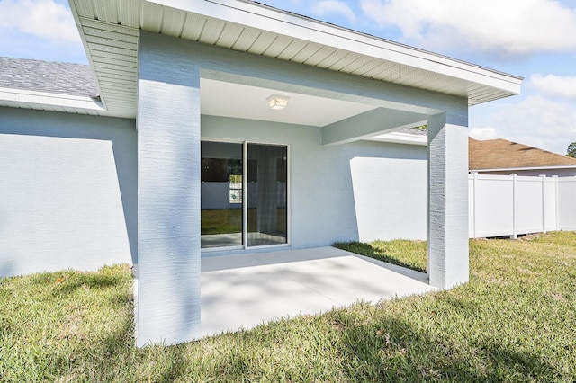 view of exterior entry with a yard and a patio