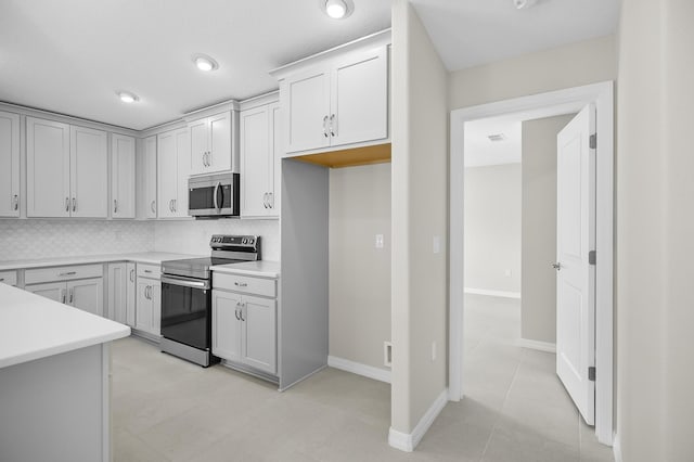 kitchen with light tile patterned floors, decorative backsplash, stainless steel appliances, and white cabinets