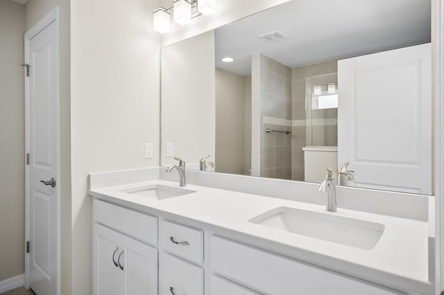 bathroom featuring tiled shower and vanity