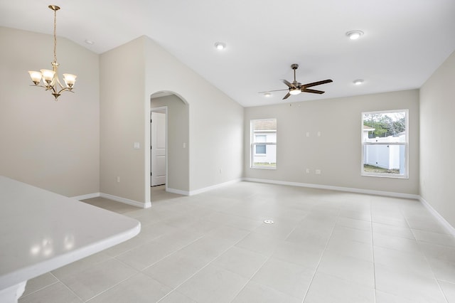 tiled empty room featuring lofted ceiling and ceiling fan with notable chandelier