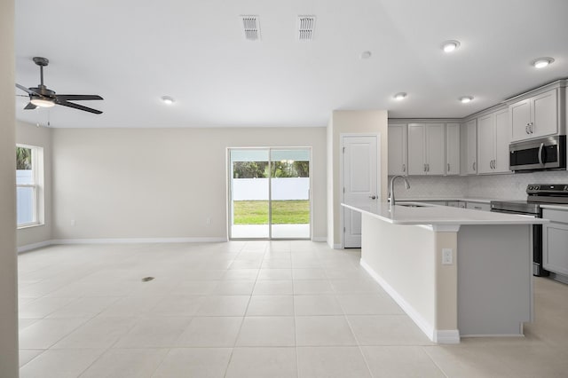 kitchen featuring appliances with stainless steel finishes, gray cabinets, and a kitchen island with sink