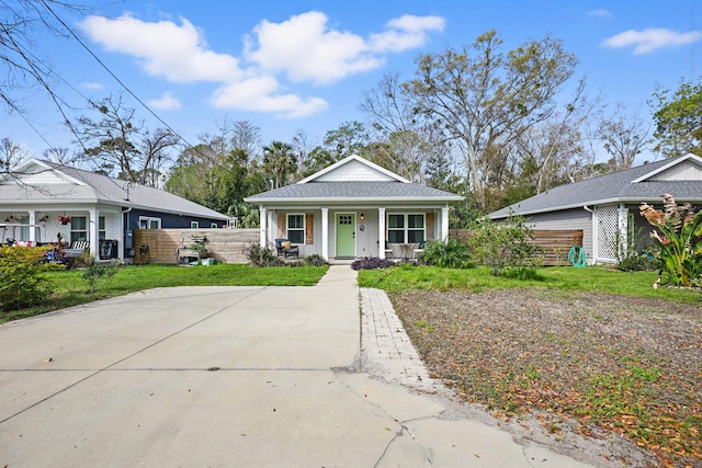 bungalow-style house featuring a porch, fence, and a front lawn