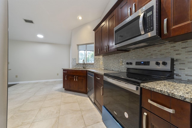 kitchen featuring lofted ceiling, backsplash, sink, light stone countertops, and stainless steel appliances