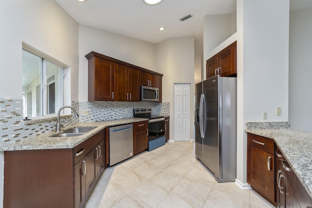 kitchen with decorative backsplash, appliances with stainless steel finishes, light stone counters, sink, and light tile patterned flooring