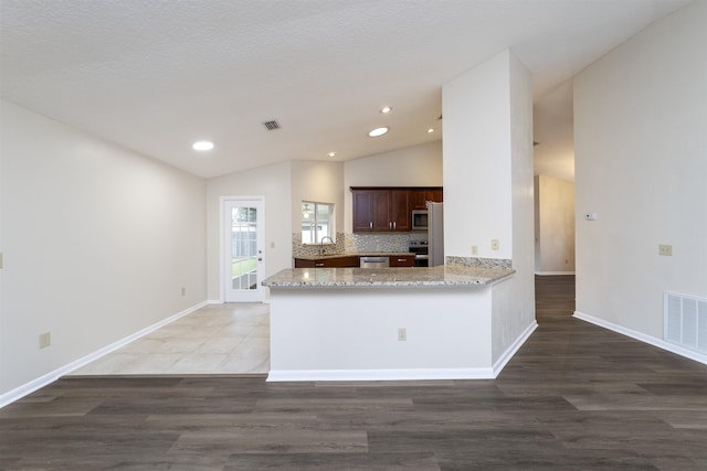 kitchen with lofted ceiling, kitchen peninsula, and dark wood-type flooring