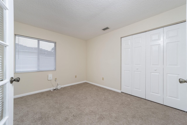 unfurnished bedroom with a textured ceiling, light colored carpet, and a closet