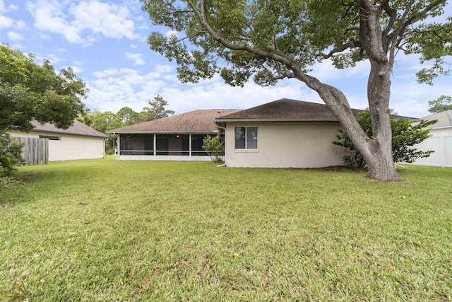 back of property with a sunroom and a lawn