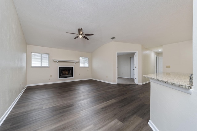 unfurnished living room featuring ceiling fan, dark hardwood / wood-style flooring, a textured ceiling, and vaulted ceiling