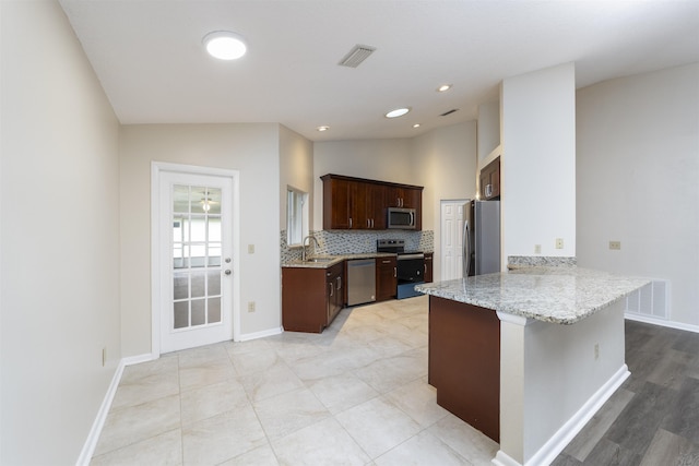 kitchen with light stone countertops, sink, stainless steel appliances, kitchen peninsula, and lofted ceiling