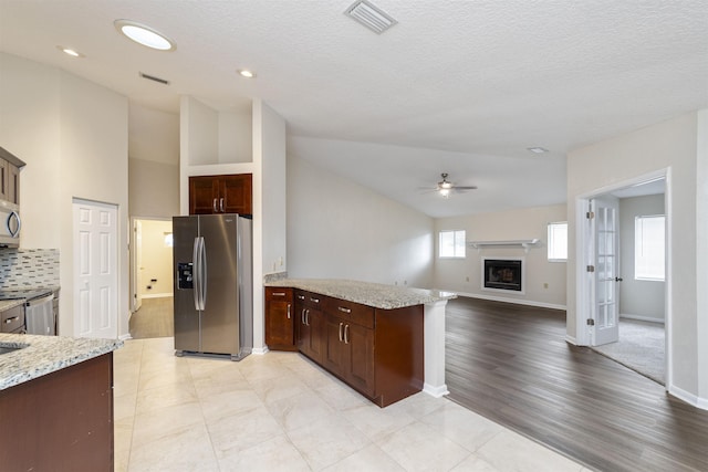 kitchen with lofted ceiling, light hardwood / wood-style flooring, ceiling fan, light stone countertops, and stainless steel appliances