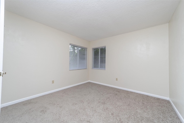 carpeted spare room with a textured ceiling