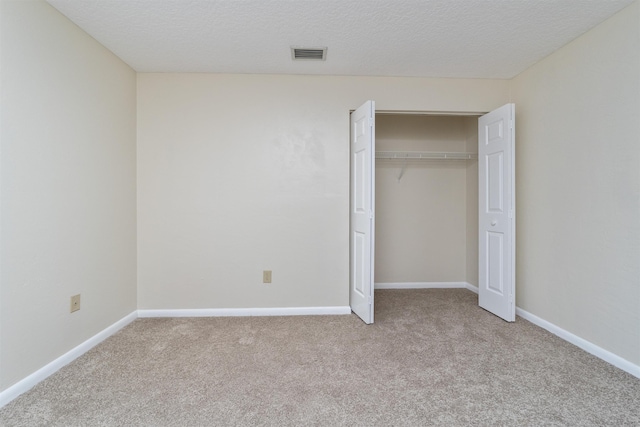 unfurnished bedroom with light carpet, a closet, and a textured ceiling